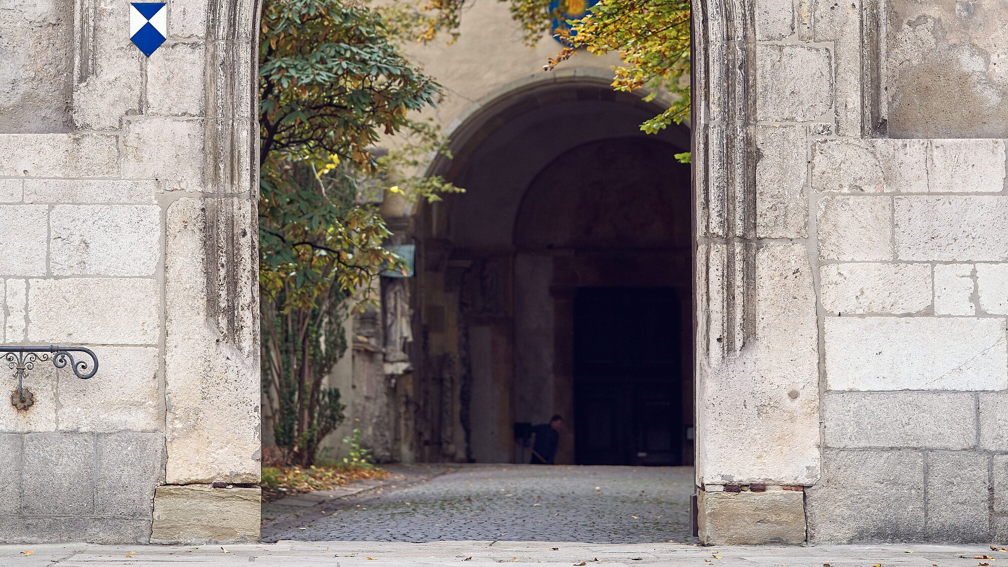 Blick auf einen steinernen Rundbogen, der in eine Kirche führt.