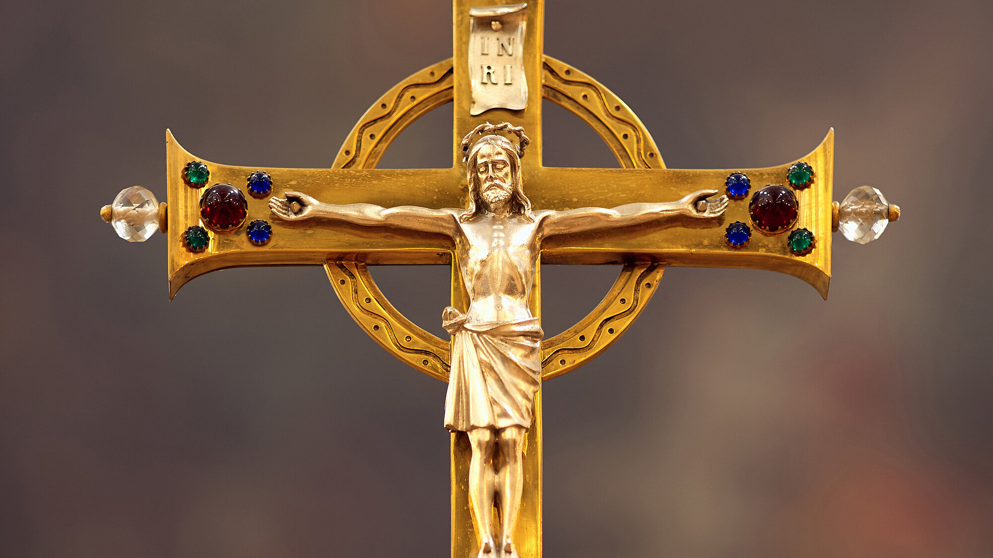 Eine Jesusfigur an einem goldenen Kreuz.